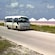 A shuttle bus drives down the road near white pyramids and shrubs